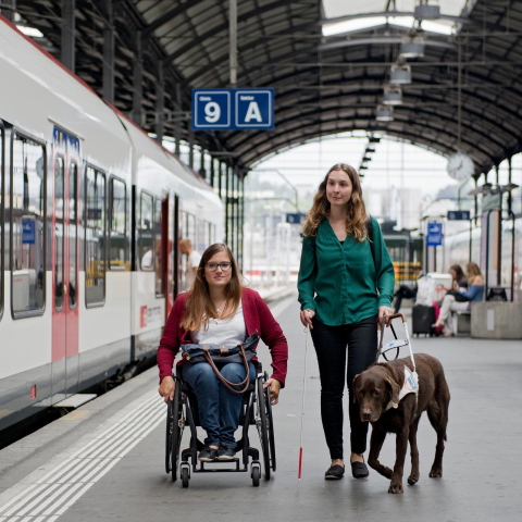 Der Tiefeinstieg zahlreicher Züge erleichtert das Ein- und Aussteigen an vielen Bahnhöfen (Foto: © SBB CFF FFS) Eine Frau im Rollstuhl und eine Frau mit einem Blindenführhund auf einem Bahnhofperron